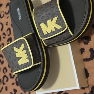 Michael Kors size 9 women slides Brown in color with a off yellow emblem